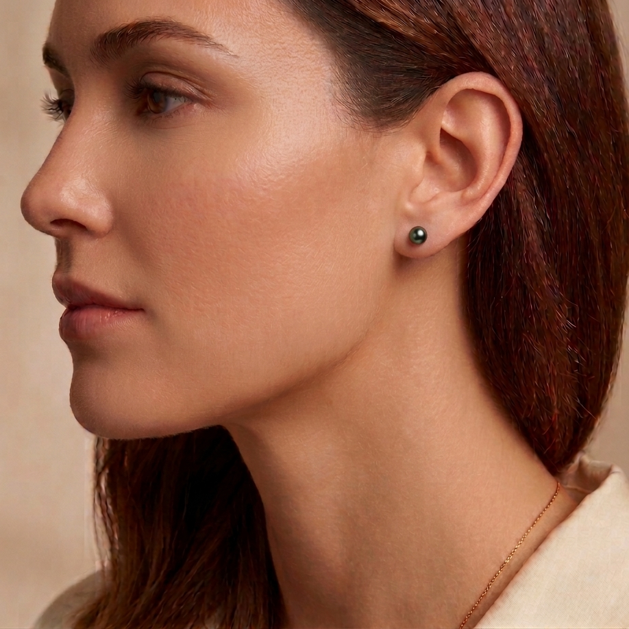 Close-up of a woman wearing a black earring against a neutral background