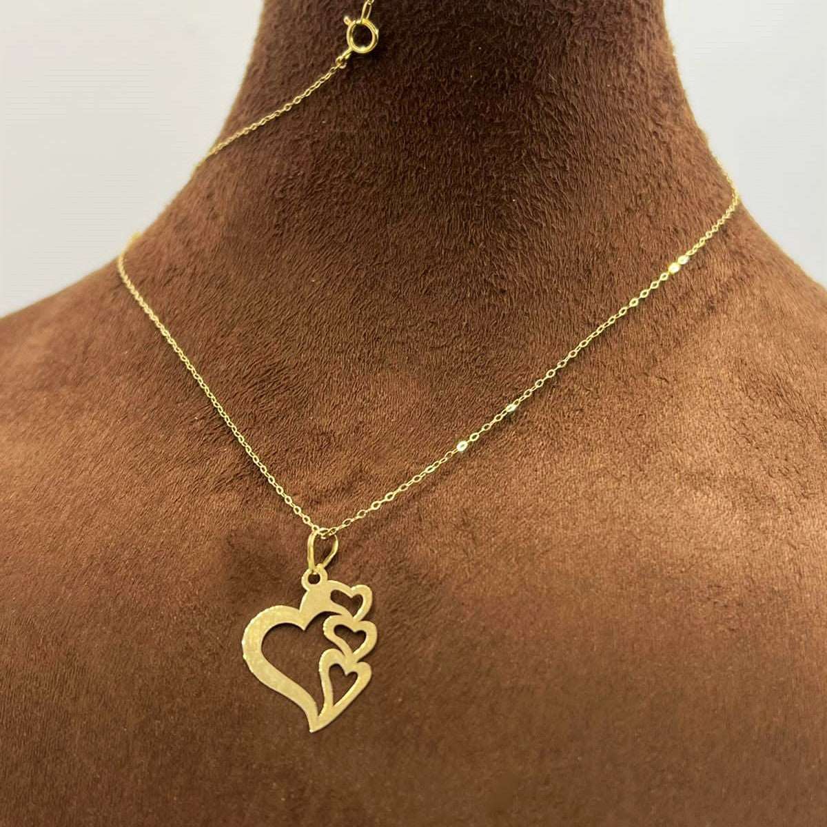 Gold necklace with three interlocking heart pendants on delicate chain, displayed on bust
