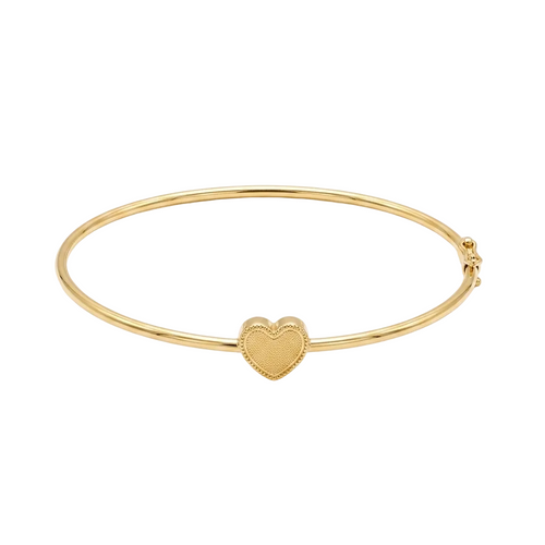 Gold bangle with a heart charm on a white background