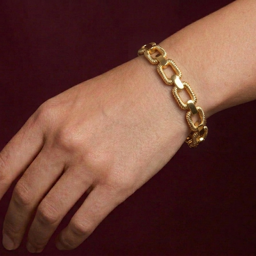 Gold butterfly bracelet on a wrist against a dark background