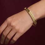 Gold butterfly bracelet on a wrist against a dark background