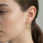 Gold hoop earrings on a gray background with weight label.